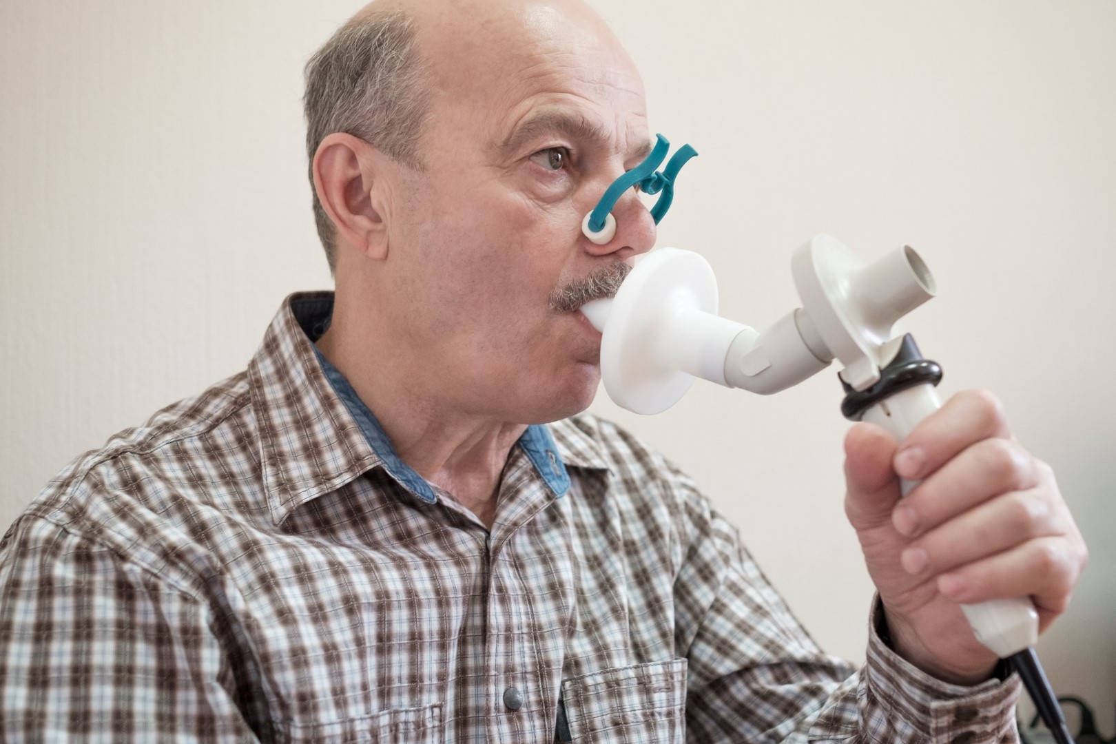 Senior hispanic man man testing breathing function by spirometry.