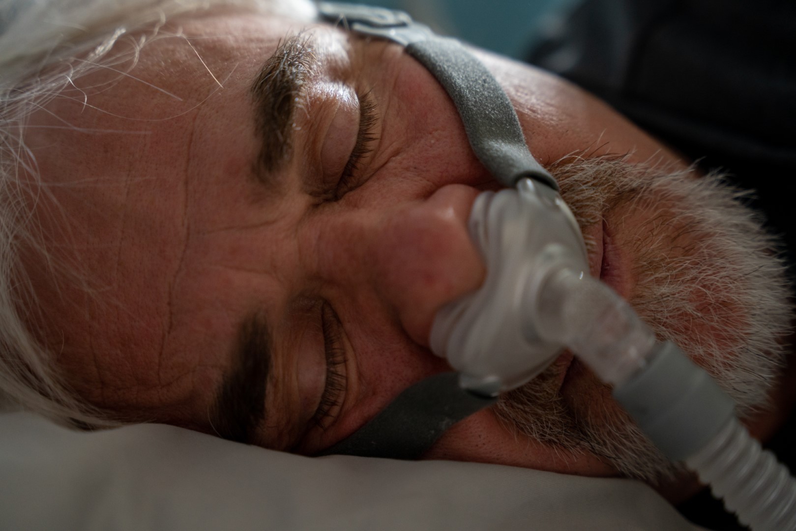 Mature Man Sleeping with a CPAP (Continuous positive airway pressure) Machine after being diagnosed with Sleep Apnea